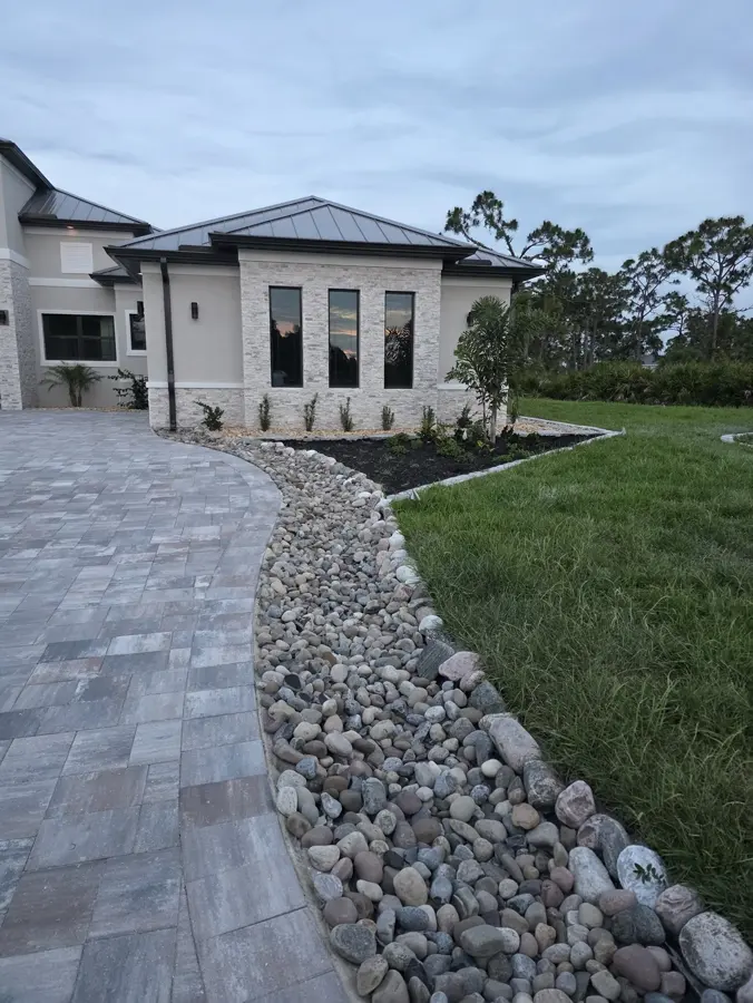Curved dry creek rock bed alongside a paver driveway