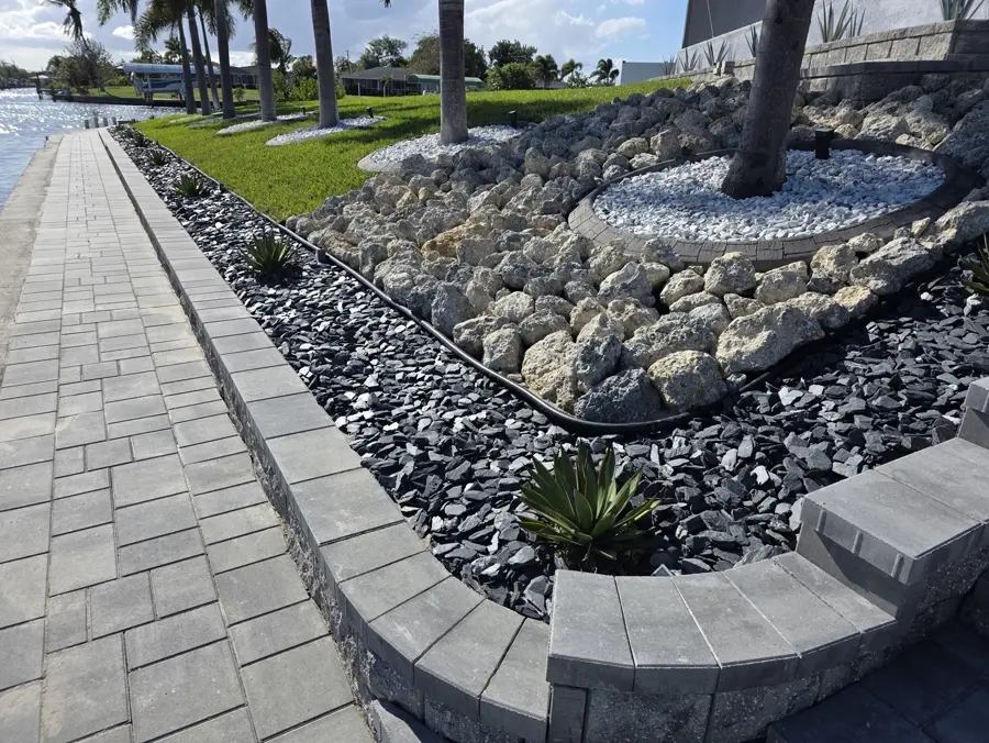 Waterfront rock landscape with paver walkway leading to a dock