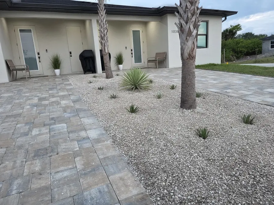 Paver entry walkway with gravel bed and palm trees at a modern home