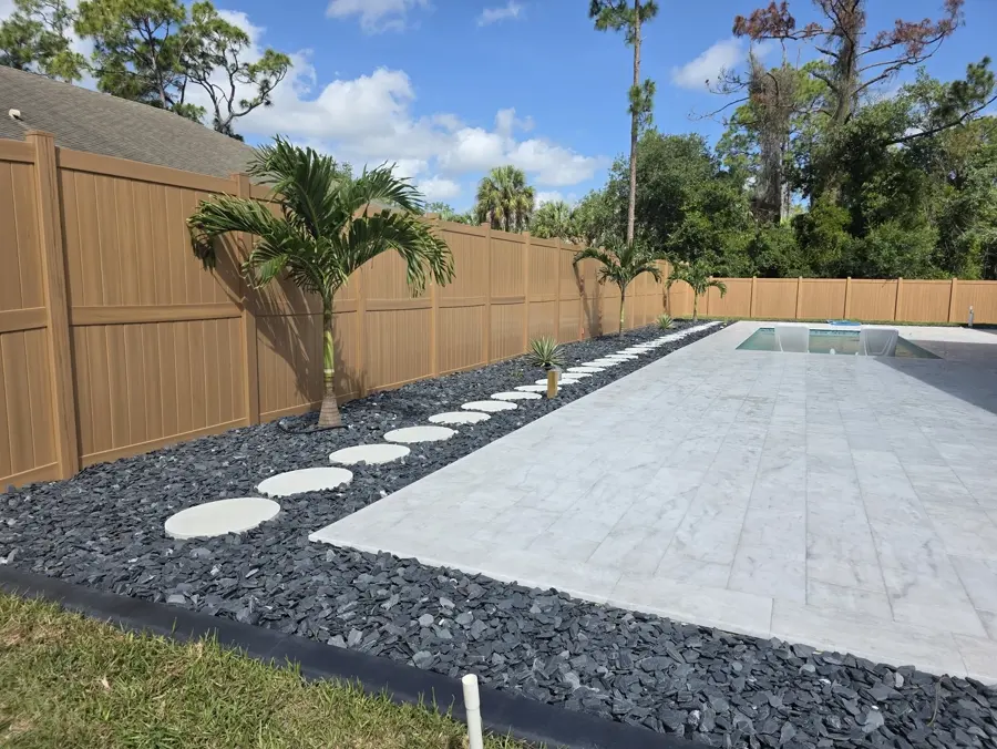 Paver pool deck with black rock landscaping and stepping stones