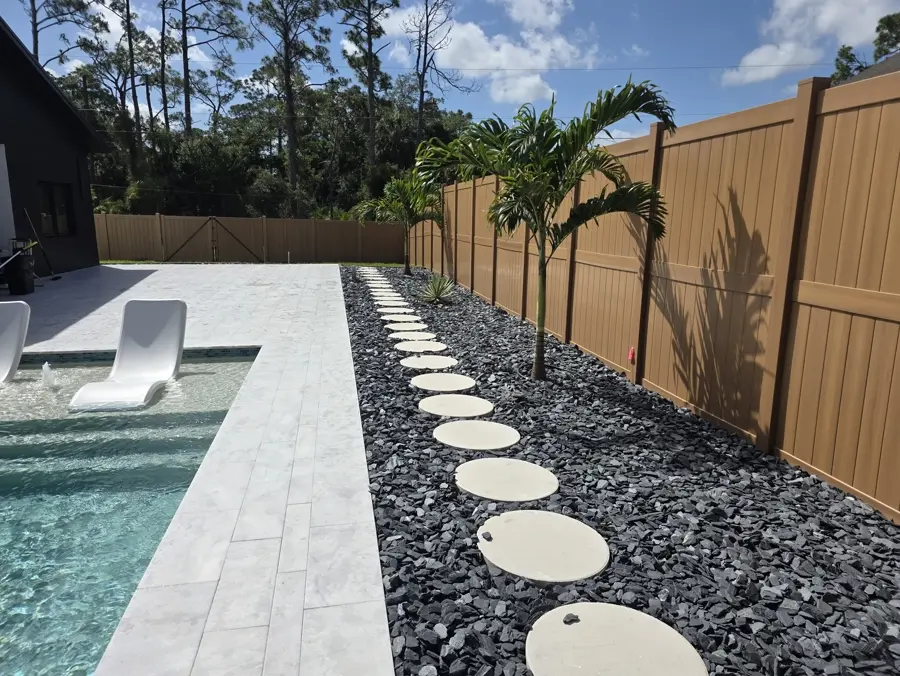 Travertine pool deck with a black rock stepping stone path and young palms