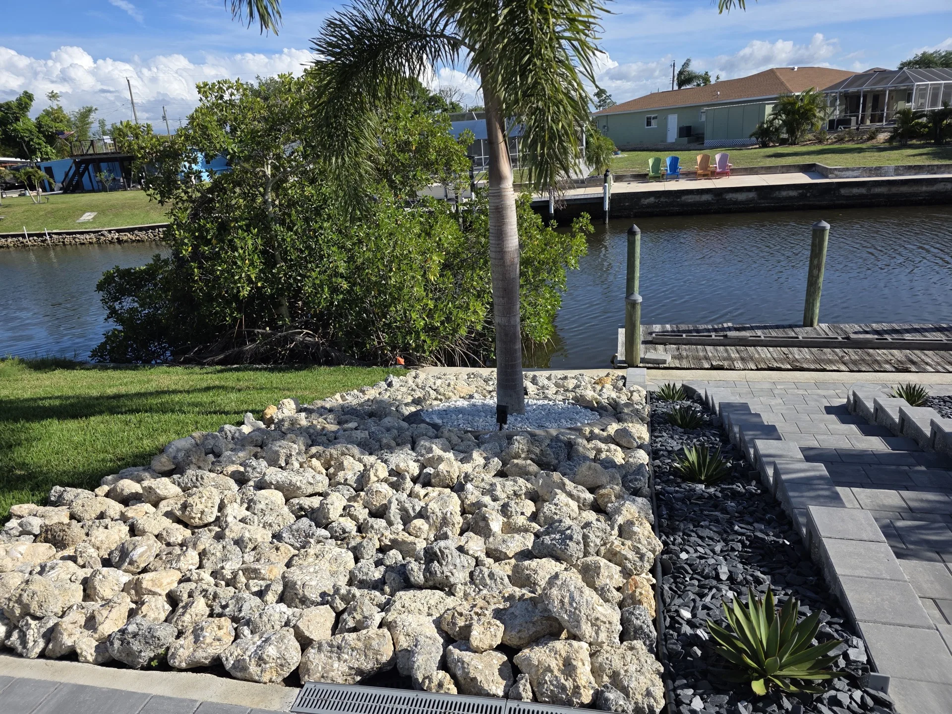 Waterfront rock landscaping with agave plants and paver edging
