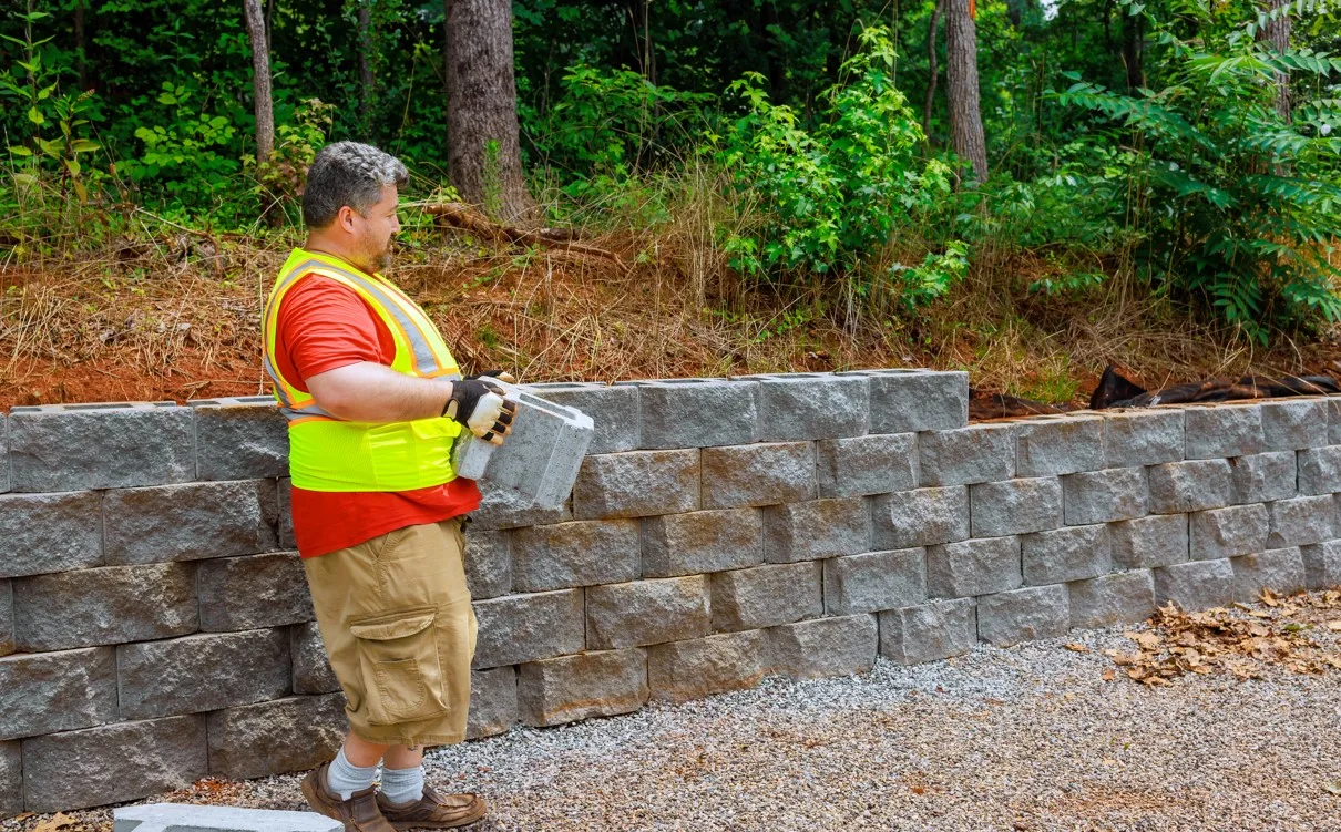 Retaining wall blocks being stacked with backfill