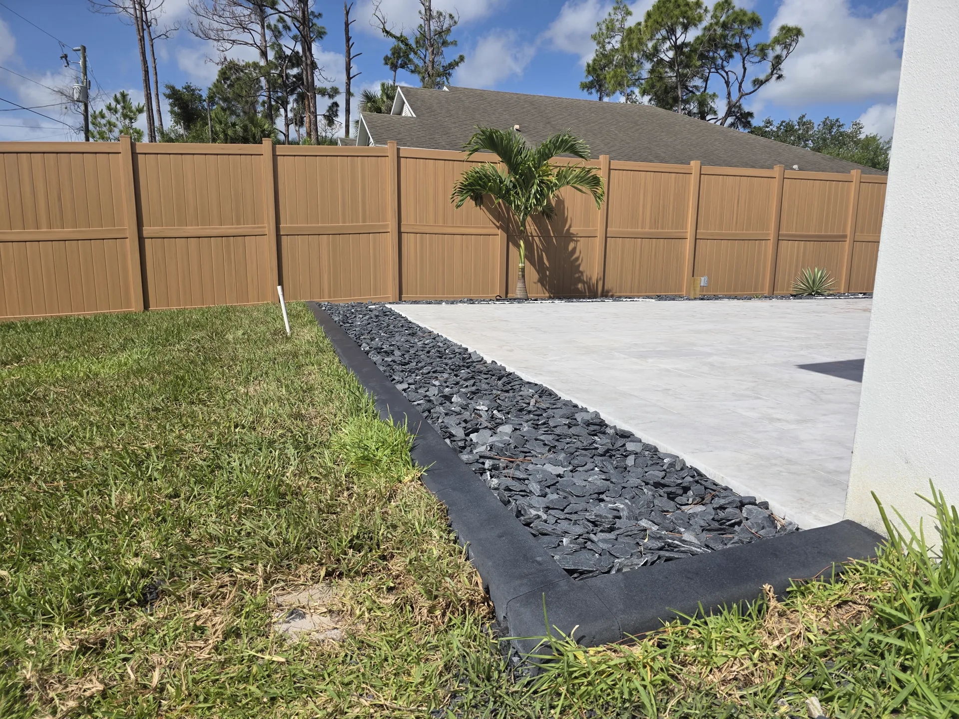 Close-up of finished stamped concrete curb beside river rock and lawn