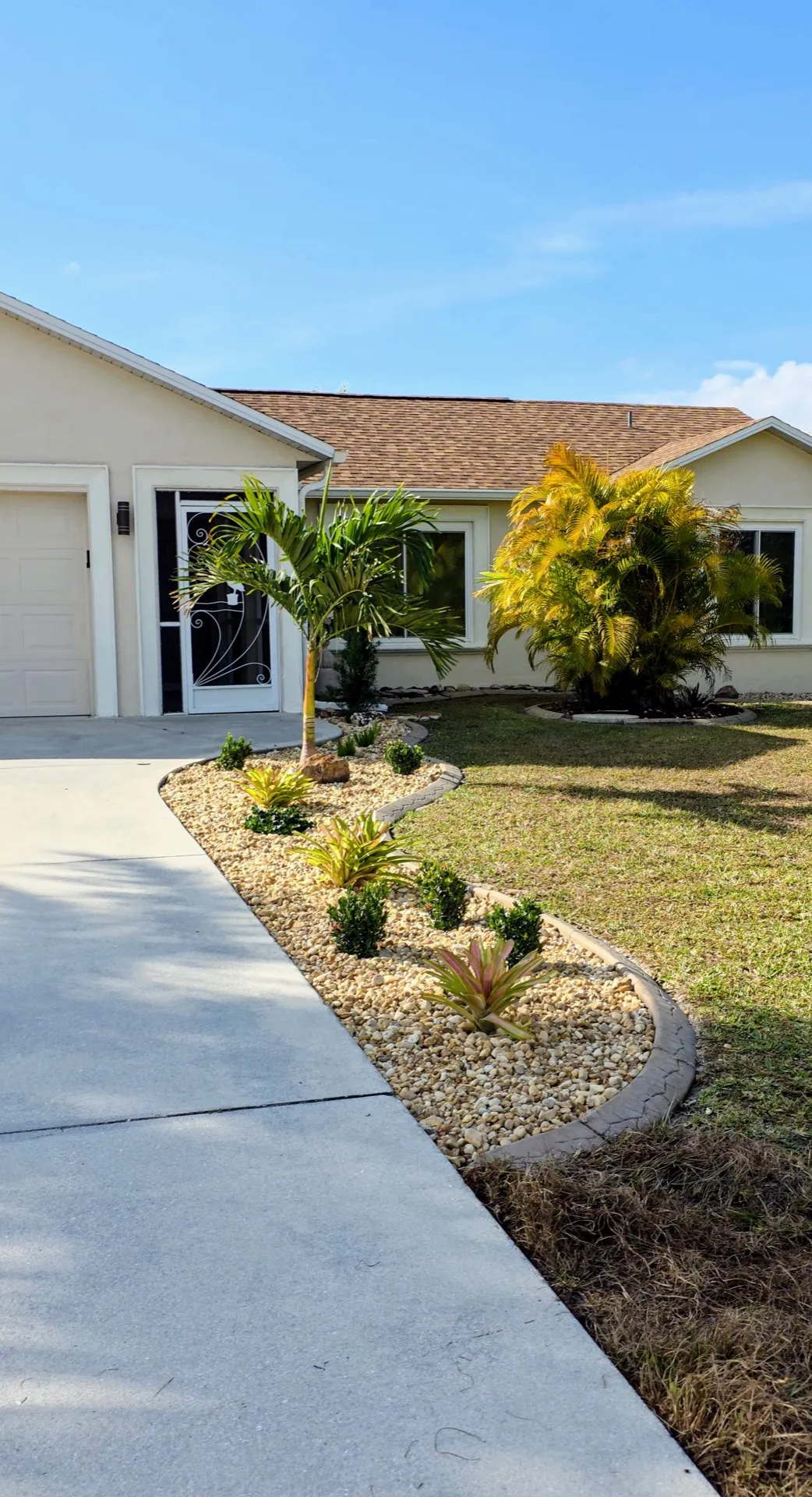 Concrete curbing with white rock mulch and tropical palms at Florida home