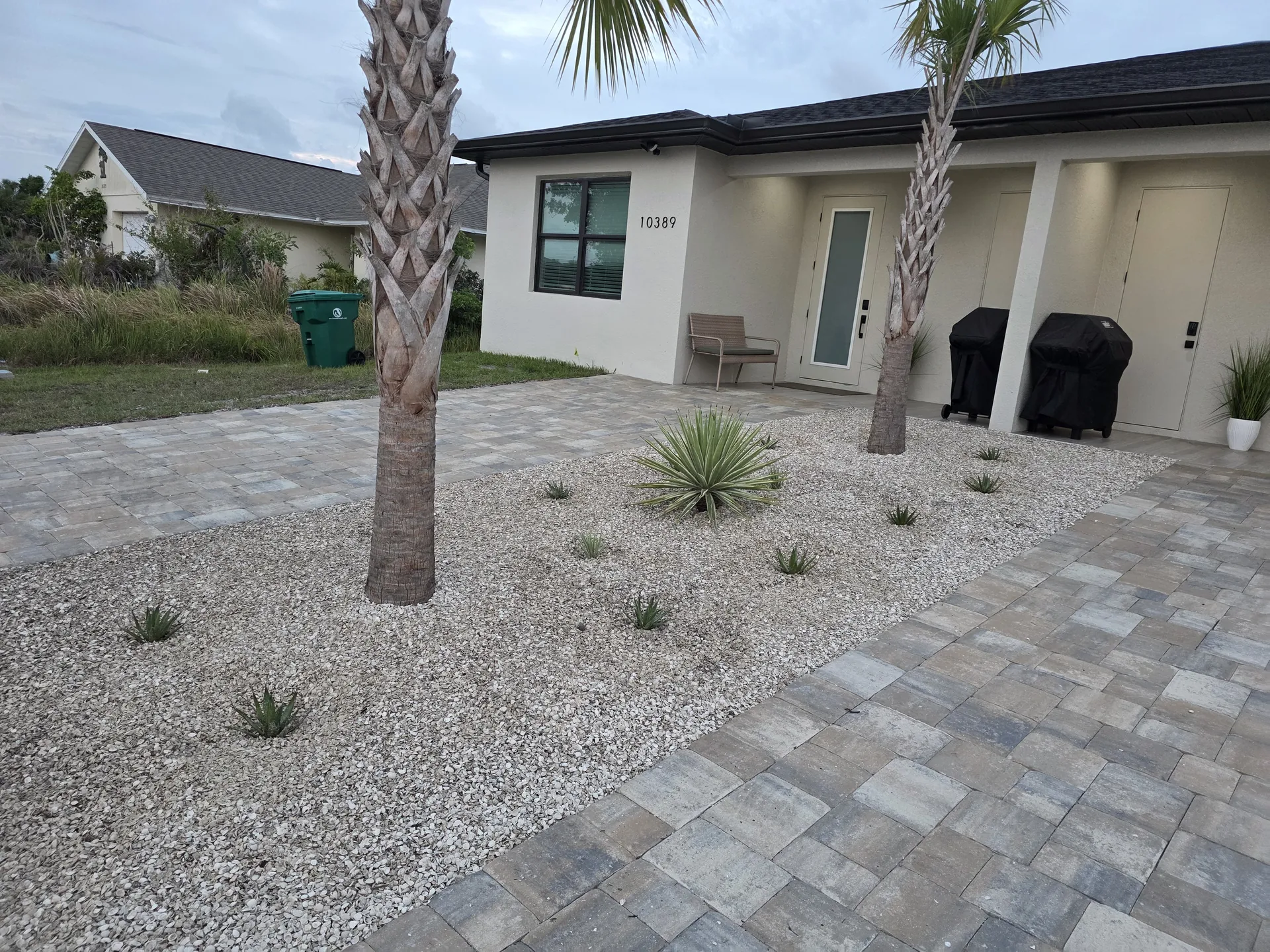 Paver driveway and entry walkway with white rock and palms at Pelican Pointe Venice FL