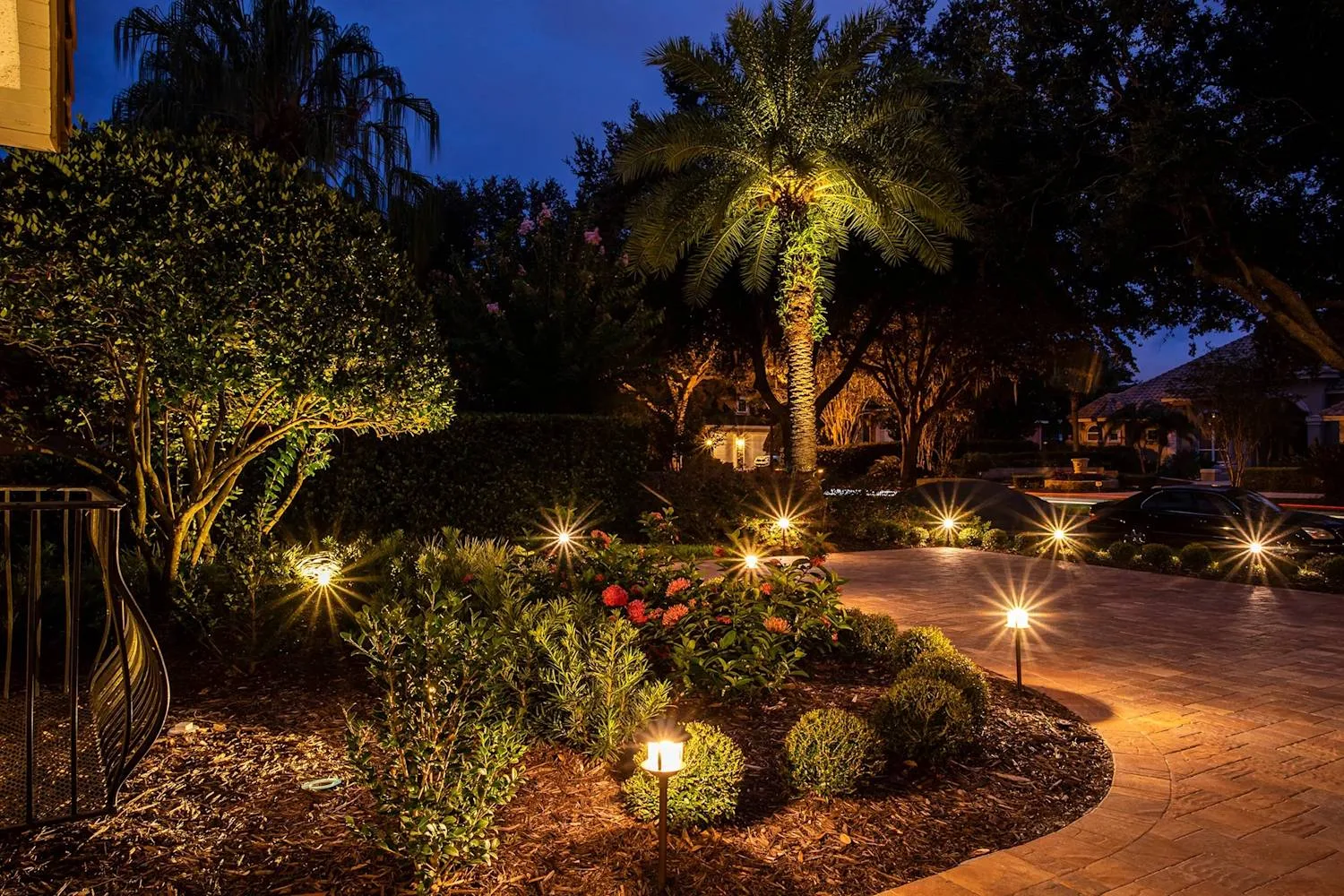 Low-voltage landscape lighting illuminating palms and paver patio at night