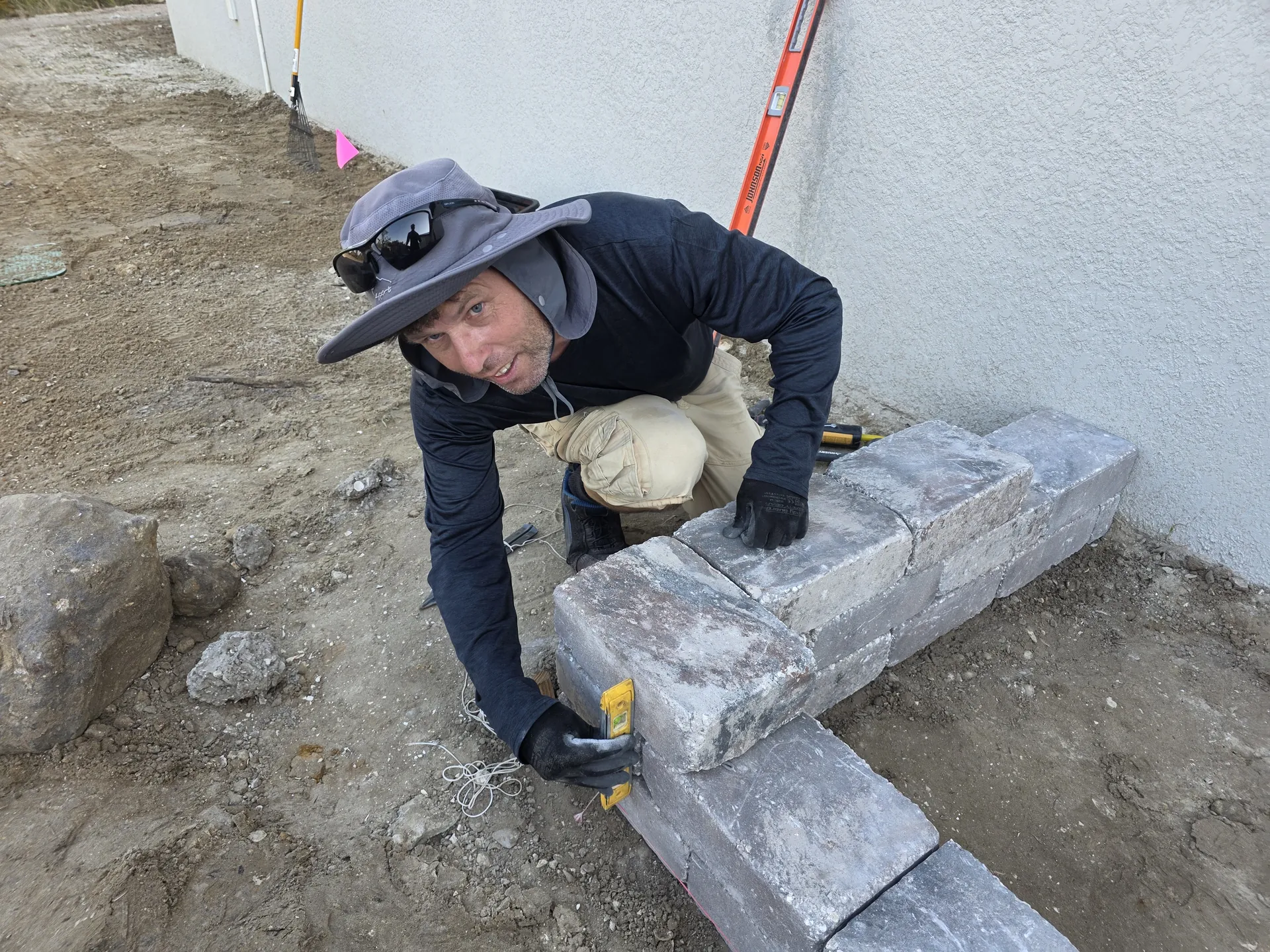 Landscaper installing block retaining wall at a canal-side property