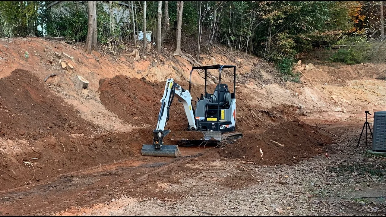 Mini excavator grading a large earthen excavation during land prep in Southwest Florida