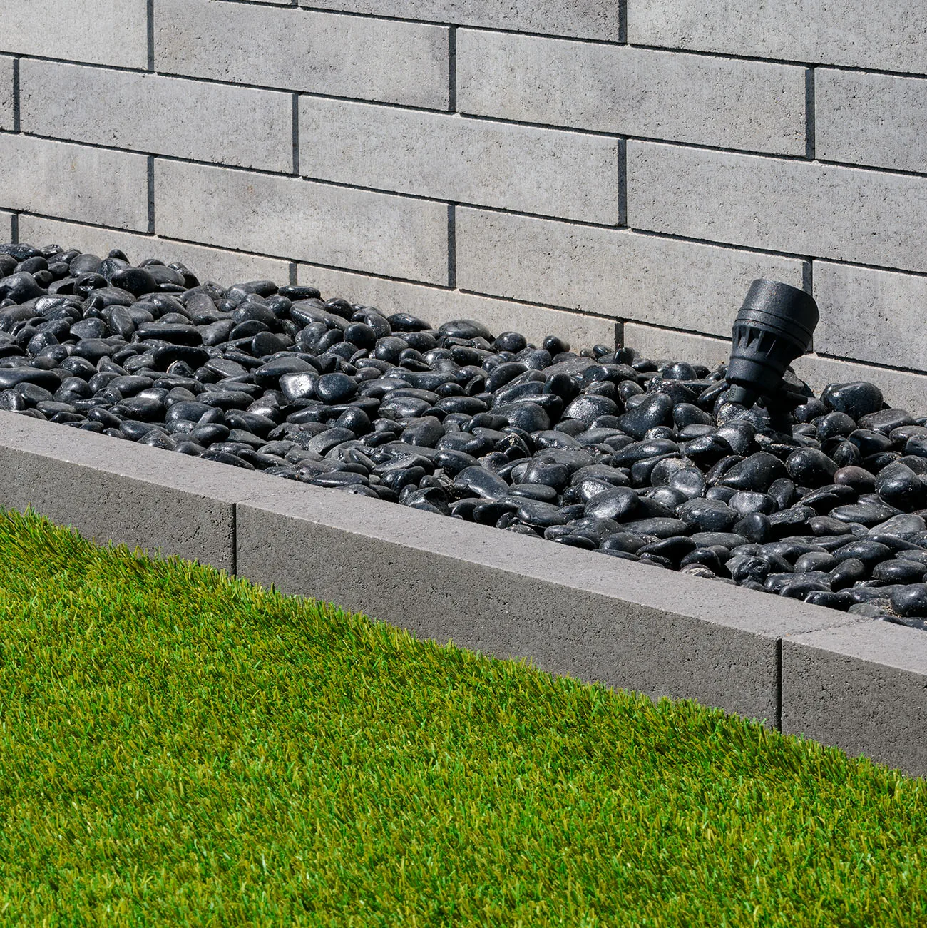 Completed concrete curbing with white rock and tropical palms from street view