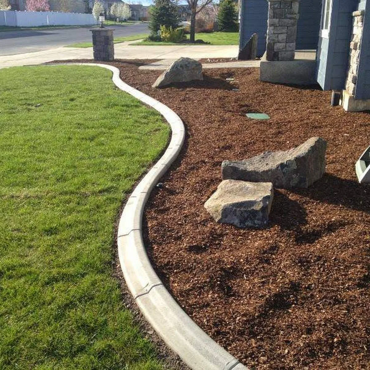 Concrete curbing with mulch bed and boulders along a lawn edge in Southwest Florida