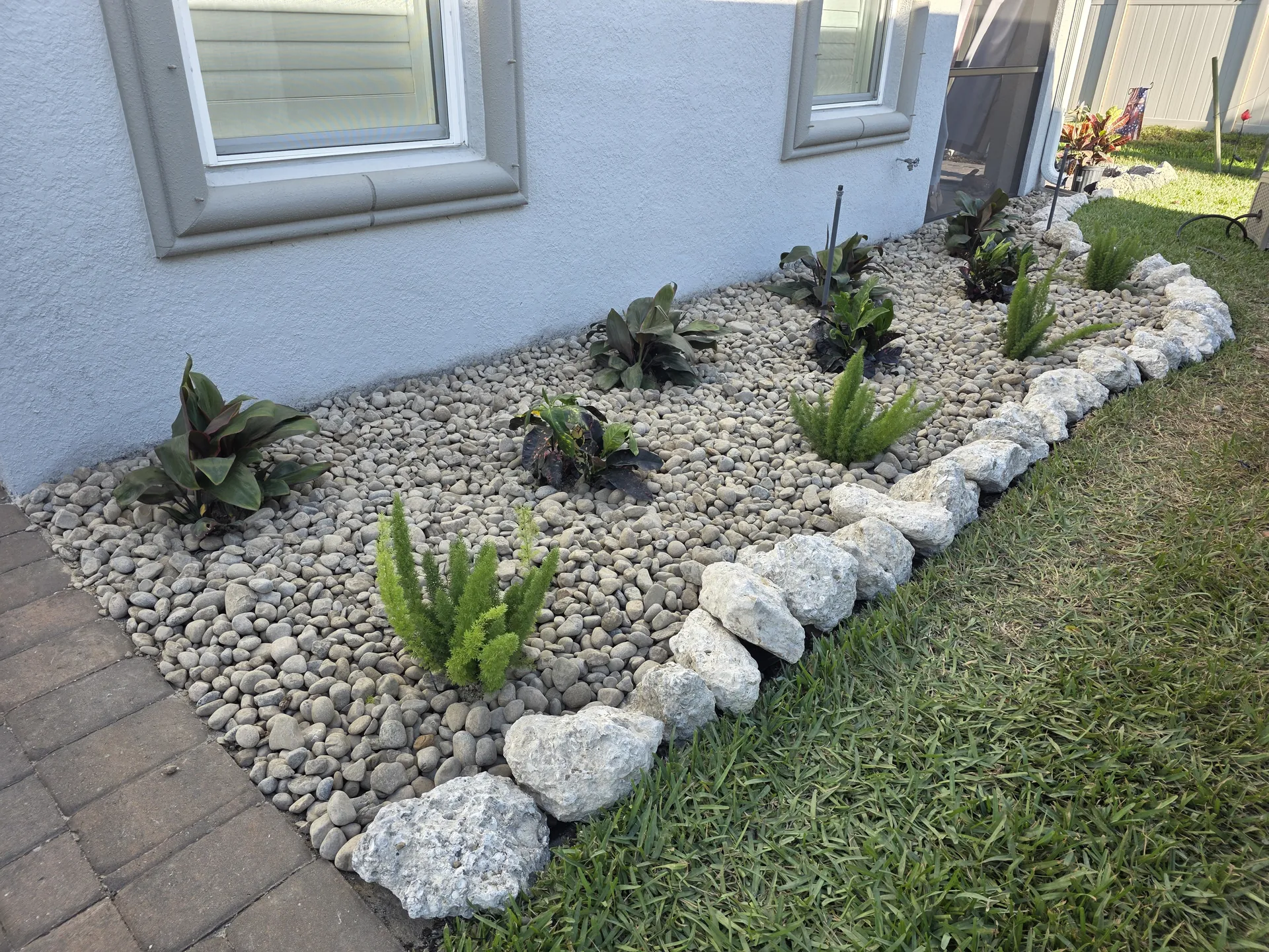River rock bed with boulder border and ferns after re-establishing the bed edge