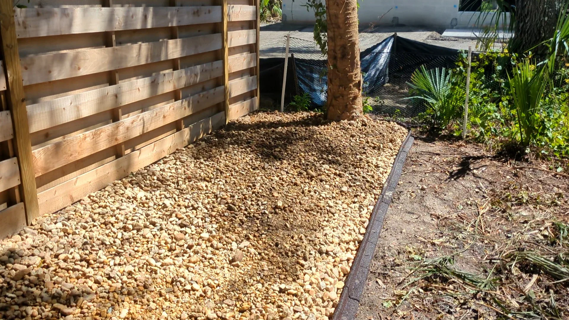 Pea gravel bed with palm and concrete curbing edging at a Charlotte County home