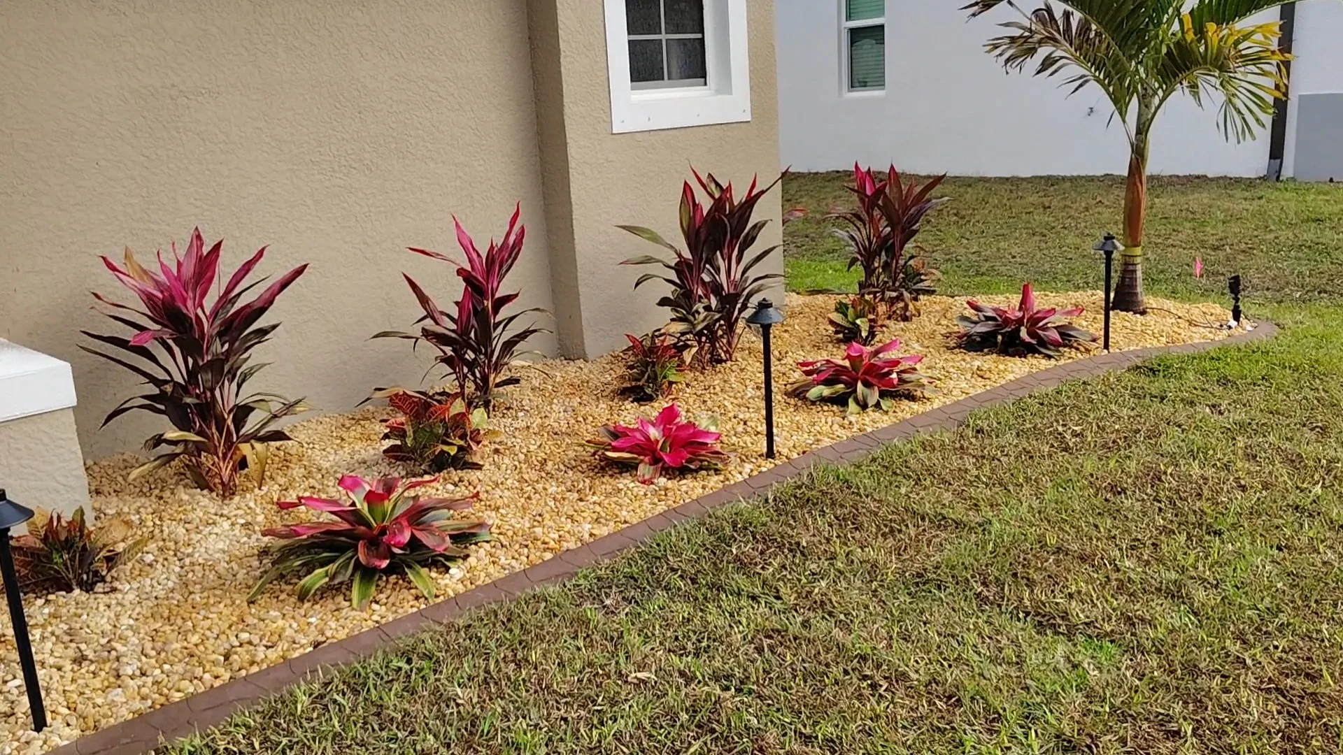 Curbing with rock beds, tropical plants, and landscape lighting at a Southwest Florida property