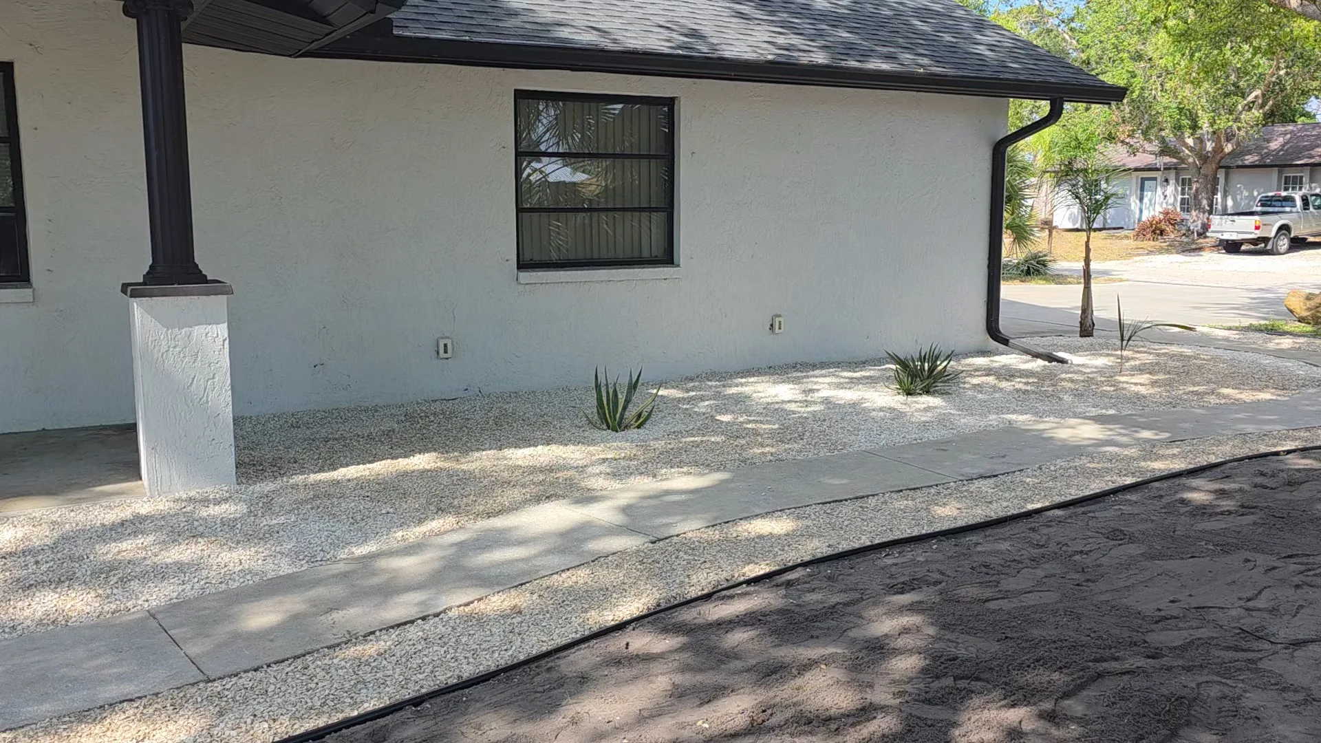 Finished Florida home landscape with white rock, palms, and arched entry