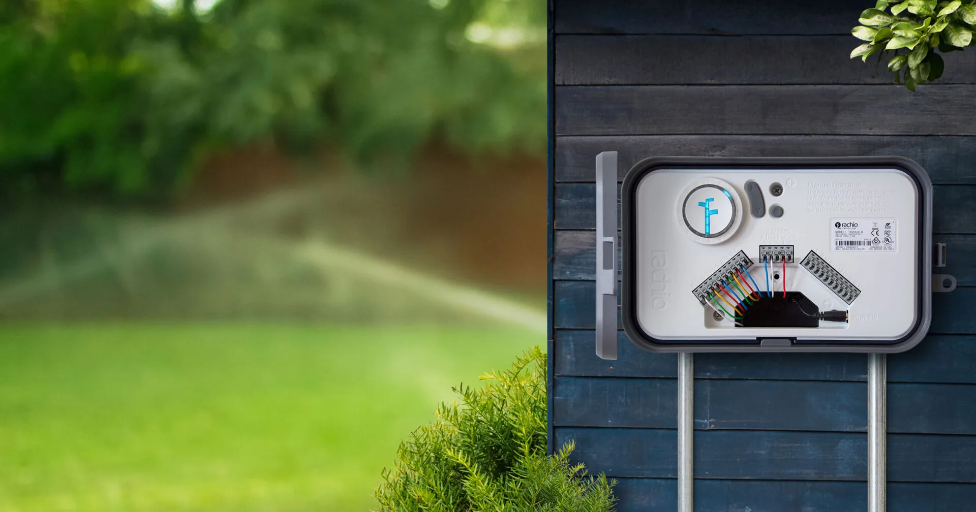 Rachio smart irrigation controller mounted on an exterior wall with sprinkler running